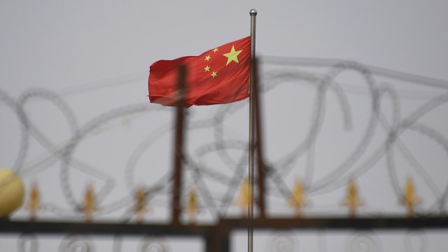 The Chinese flag flies behind razor wire at a housing compound south of Kashgar, China, in 2019. (Greg Baker/AFP via Getty Images)