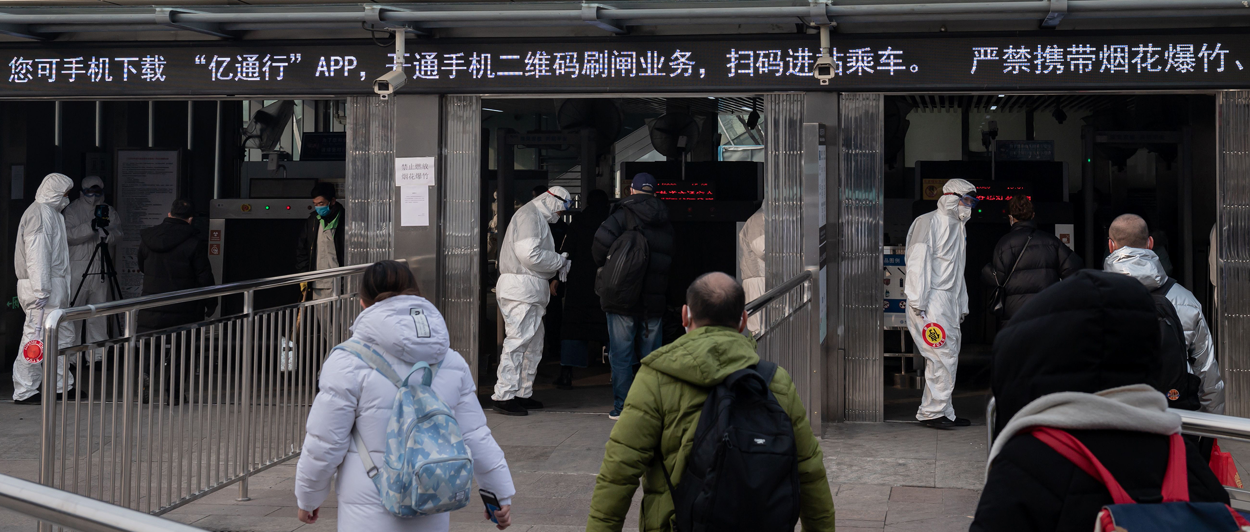 Photo showing security personnel wearing protective clothing check the temperatures of people entering a subway station in Beijing in January 2020 as part of the country's strict "zero COVID" policy. (Nicolas Asfouri/AFP via Getty Images)