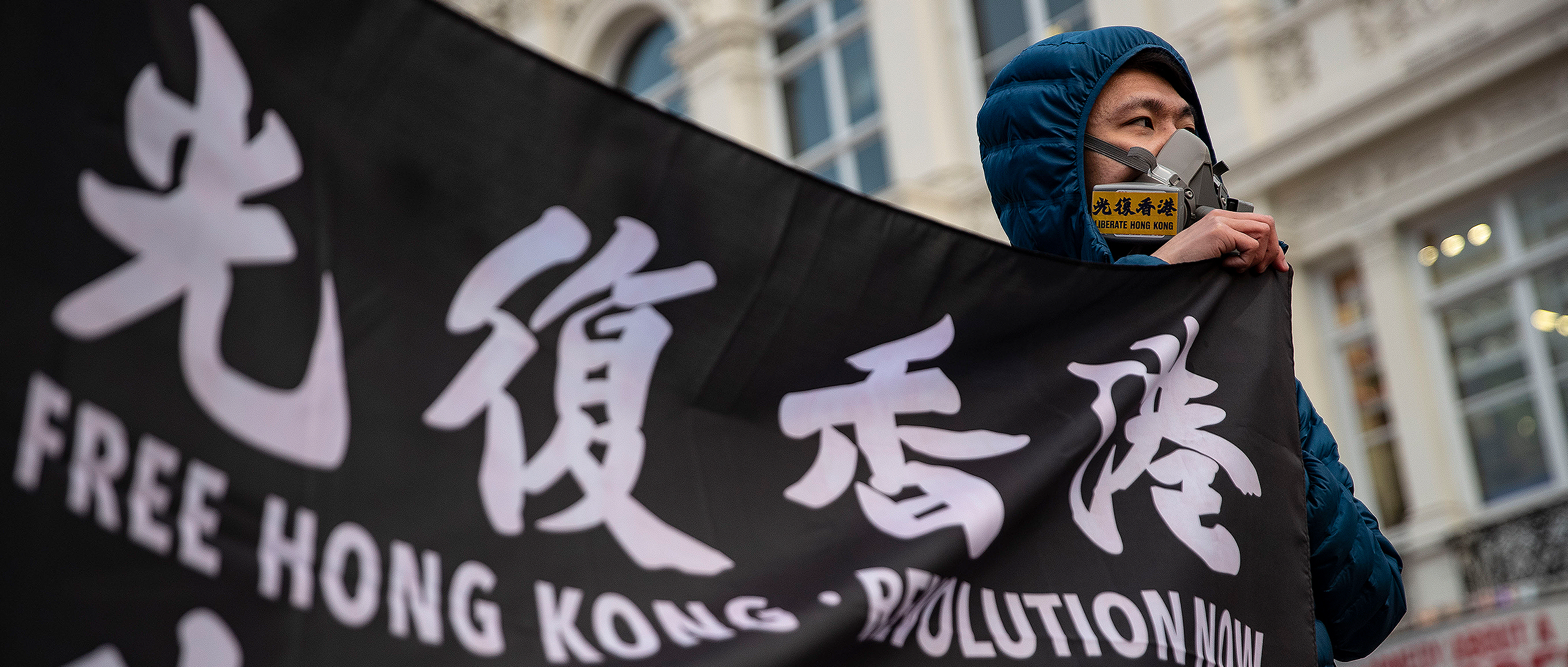 Photo showing a Hong Kong supporter holds a banned flag saying "Free Hong Kong, Revolution Now" during protests in Piccadilly Circus in London in March 2021. (May James/SOPA Images/LightRocket via Getty Images)