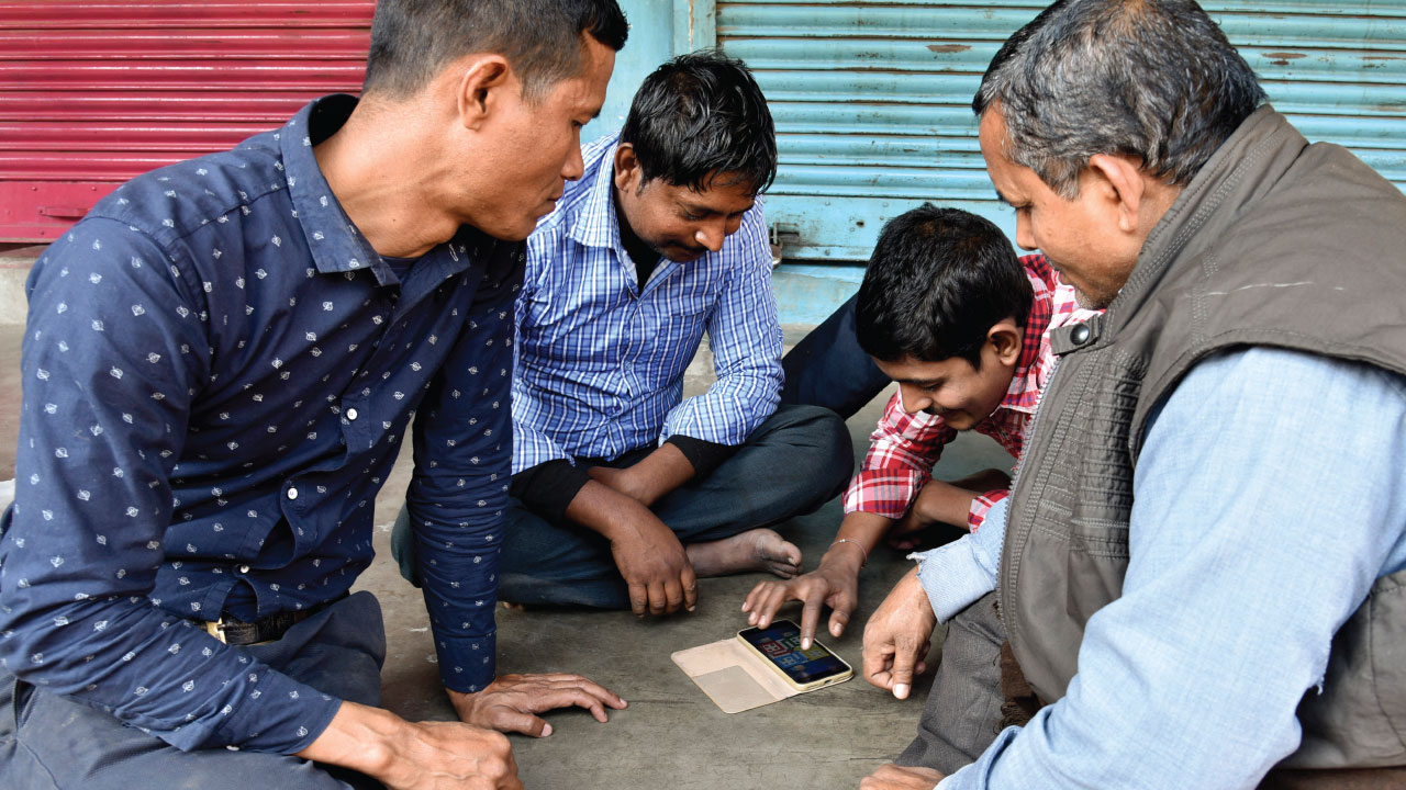 Shopkeepers in Guwahati, India, playing a game on a mobile phone. (David Talukdar/NurPhoto via Getty Images)