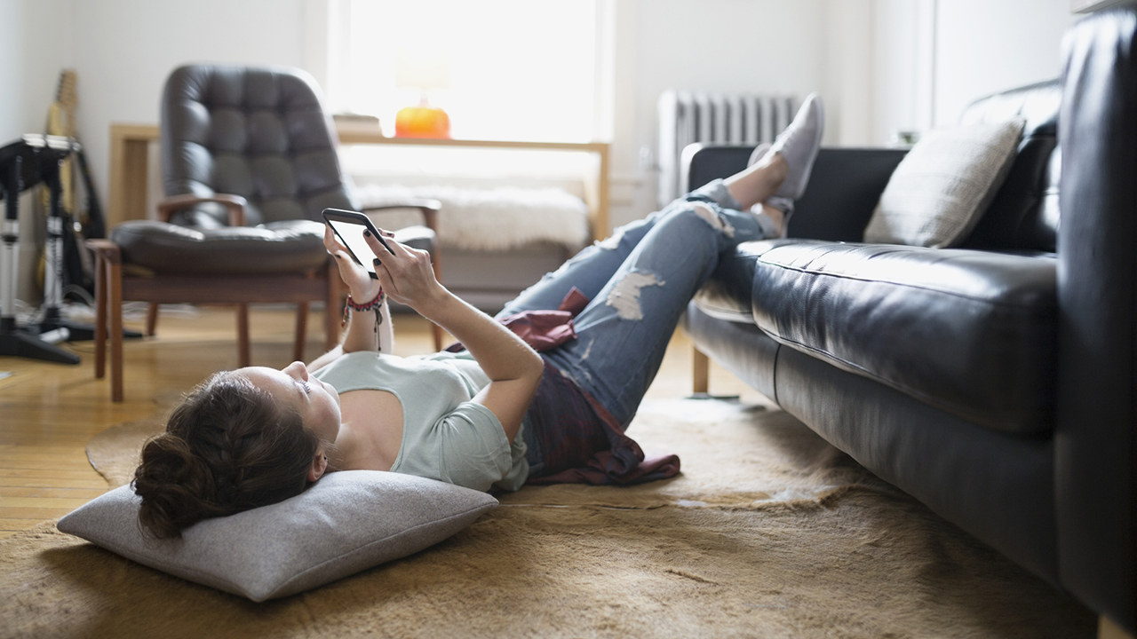 Photo of a woman laying with feet up texting cell phone