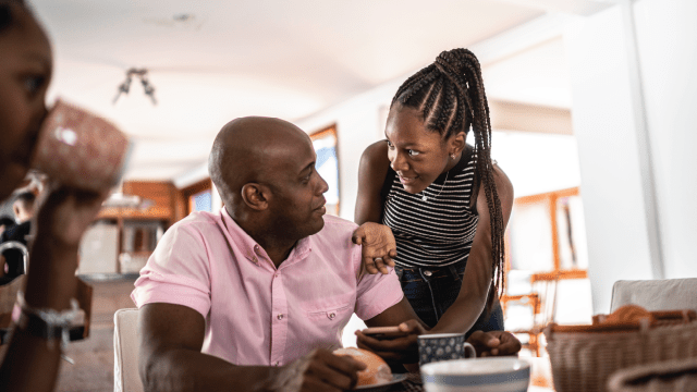 An image of a father and teen daughter in discussion while using a smartphone.