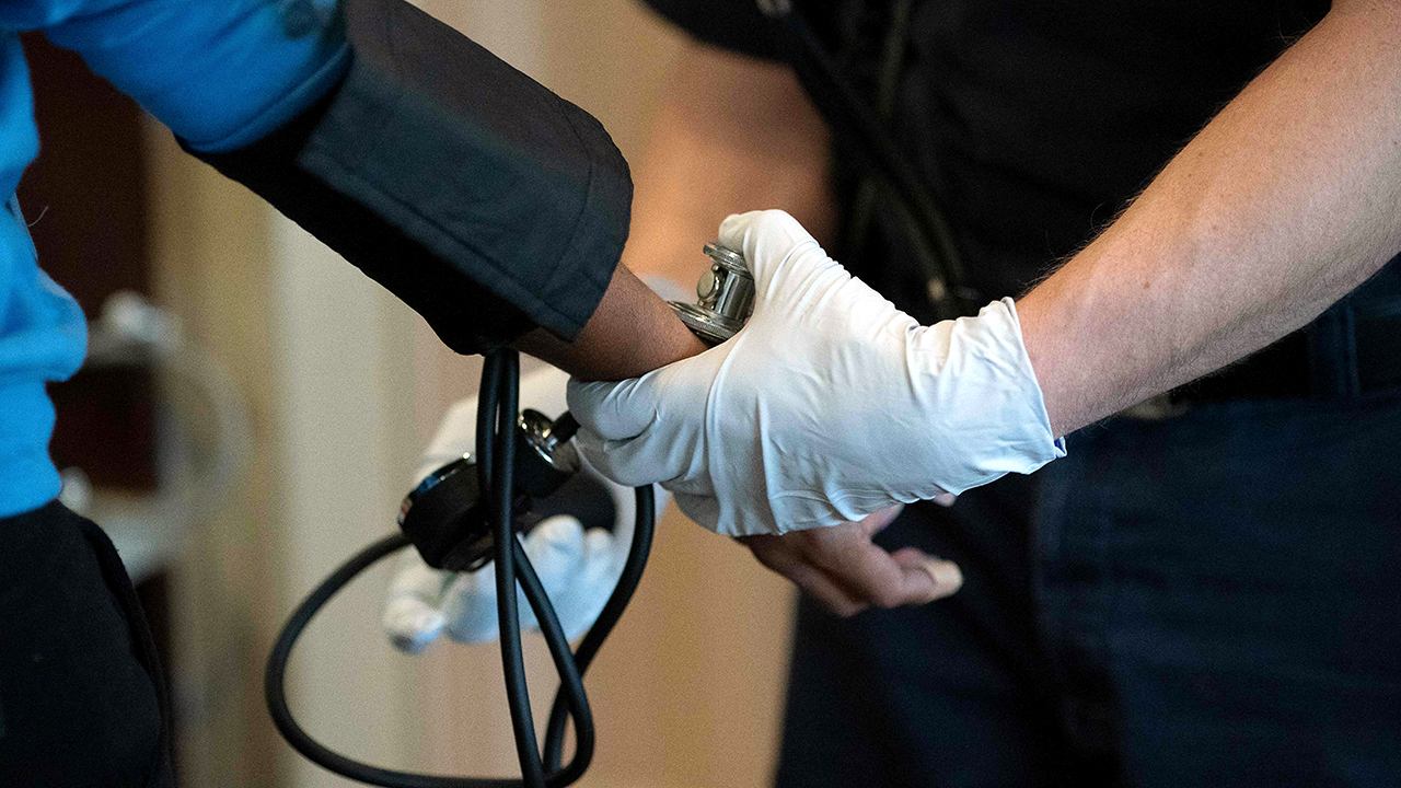 A paramedic takes the blood pressure of a patient as he responds to a medical call (Alex Edelman/AFP via Getty Images)