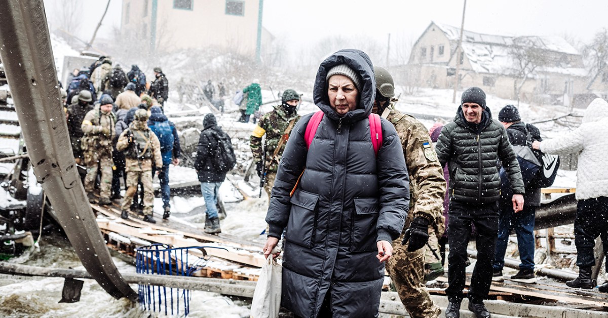 A photograph shows a woman crossing a destroyed bridge as civilians flee Irpin, Ukraine due to ongoing Russian attacks on March 8, 2022