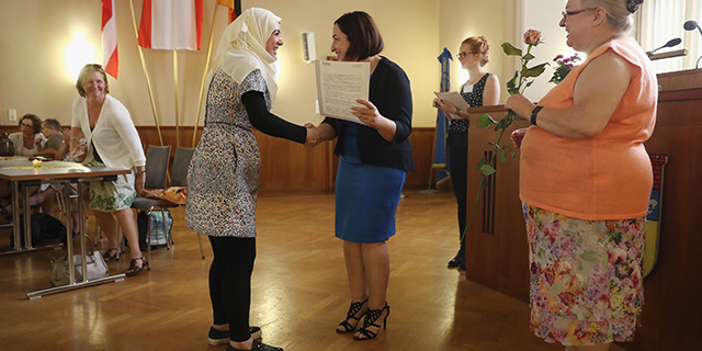 Syrian refugee Marwad Khaled, center left, is awarded a completion certificate for a beginner's level German language class by Dilek Kolat, Berlin state senator for Work, Women and Integration, in Berlin in July 2016. The language program is financed by the city of Berlin to train more than 20,000 of the refugees granted asylum in Germany. (Sean Gallup/Getty Images)