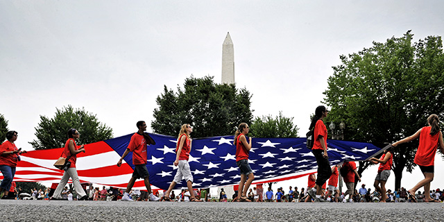 Volunteers carry an American flag down Constitution Avenue during the National Independence Day Parade in Washington, D.C. (Bill O'Leary/The Washington Post via Getty Images)