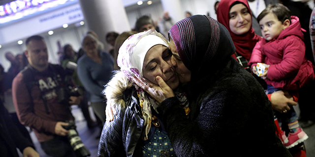 Syrian refugee Baraa Haj Khalaf receives a kiss from her mother, Fattoum Haj Khalaf, in February 2017 shortly after the family had arrived at Chicago's O'Hare International Airport. Her daughter Sham is held by her sister Aya at right. (Joshua Lott/AFP/Getty Images)