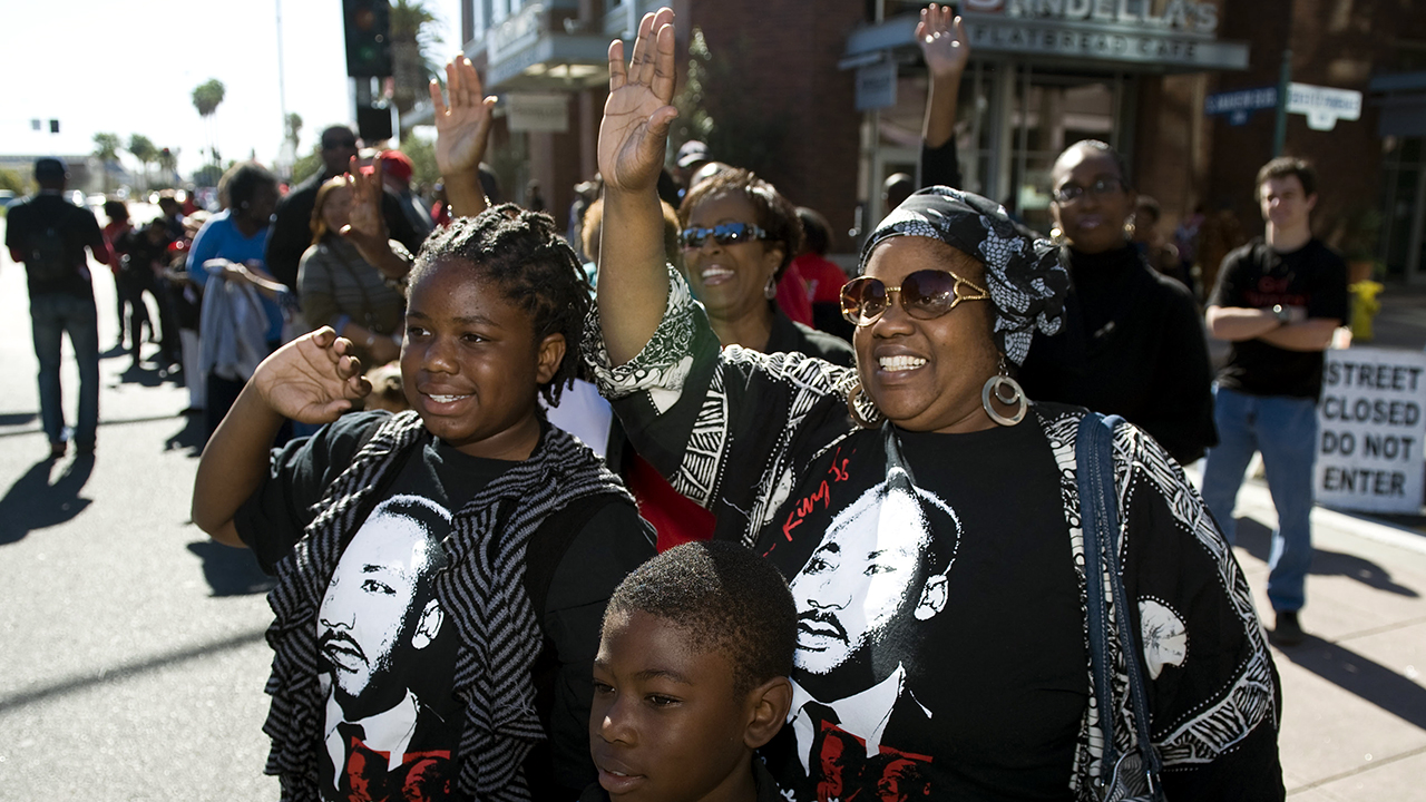 Junwanna Brisby of Anaheim waves with her children Kiara, 11, and Roosevelt, 9, during the 34th annual Orange County Black History Parade in February 2014. (Kevin Sullivan/Orange County Register via Getty Images)