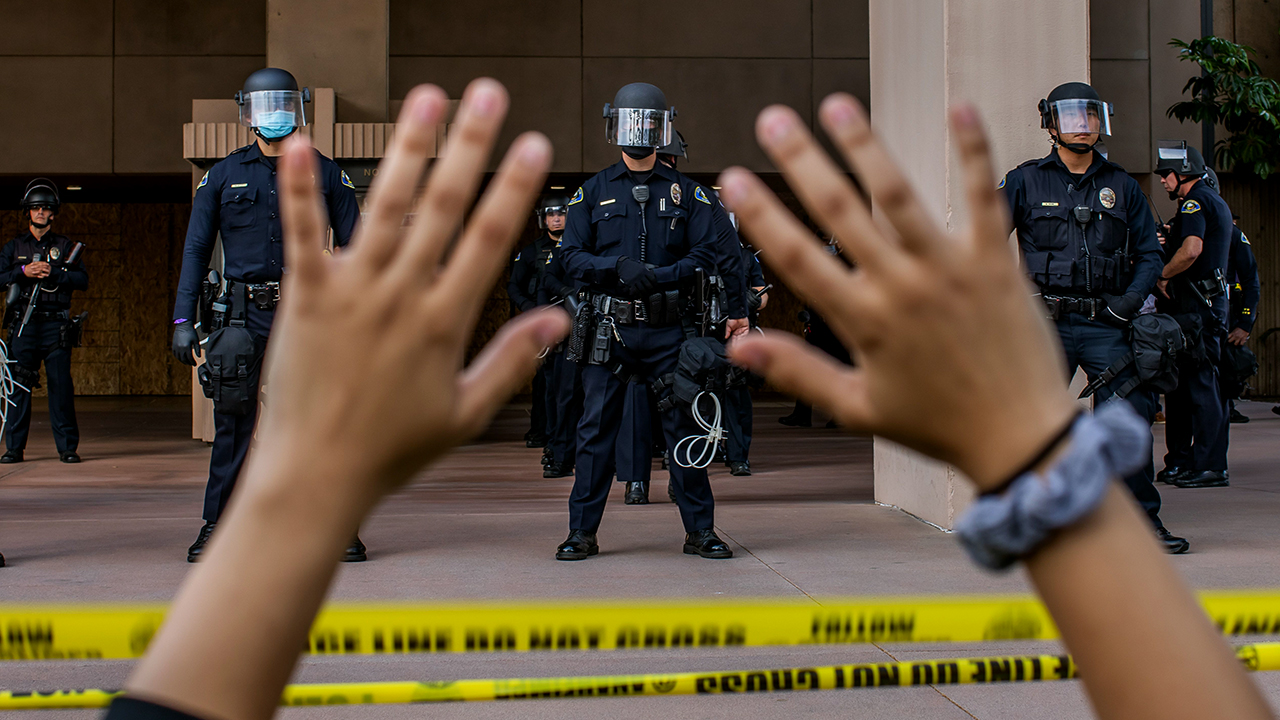 A demonstrator holds her hands up while kneeling in front of police at City Hall in Anaheim, California, on June 1, 2020, during a peaceful protest over the death of George Floyd. (Apu Gomes/AFP via Getty Images)