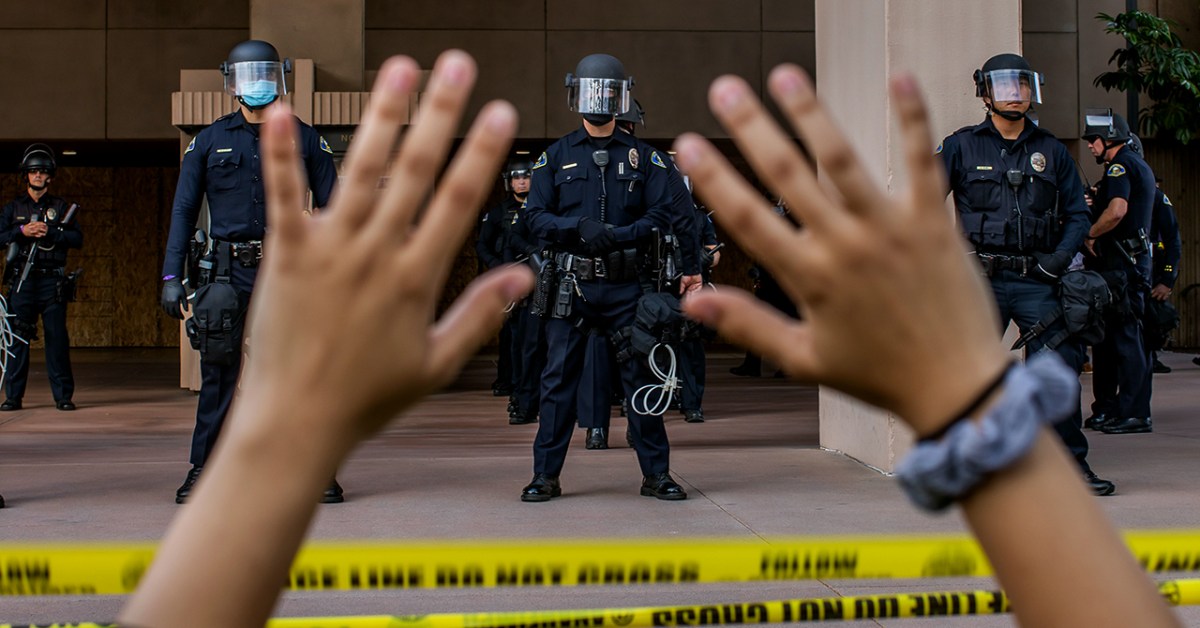 A demonstrator holds her hands up while kneeling in front of police at City Hall in Anaheim, California, on June 1, 2020, during a peaceful protest over the death of George Floyd. (Apu Gomes/AFP via Getty Images)