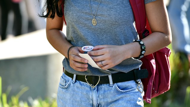 A student holds an "I Voted" sticker as she leaves a polling station on the campus of the University of California, Irvine, on Election Day 2018.