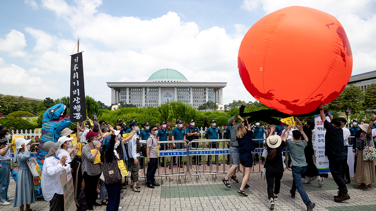 Климатические активисты держат большой красный шар, символизирующий Землю, 11 июня 2020 года в Сеуле, Южная Корея. (Крис Юнг/NurPhoto через Getty Images)