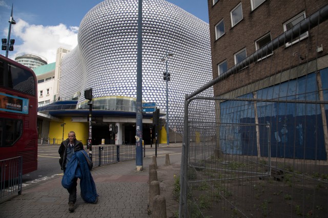 A homeless man carries his sleeping bag past the iconic Selfridges Building in Birmingham in 2017. (Mike Kemp/In Pictures via Getty Images)