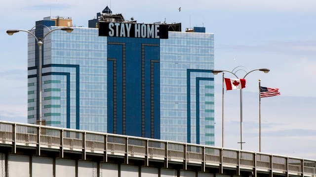 Canadian and U.S. flags are seen from the Canadian side of the Rainbow Bridge in Niagara Falls, Ontario, Canada, on May 19, 2020, along with a banner reading "stay home."