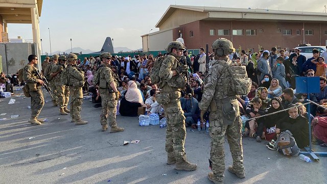 U.S. soldiers stand guard at the military airport in Kabul as Afghan people wait to board a military aircraft on Aug. 19 during the U.S. withdrawal from Afghanistan.