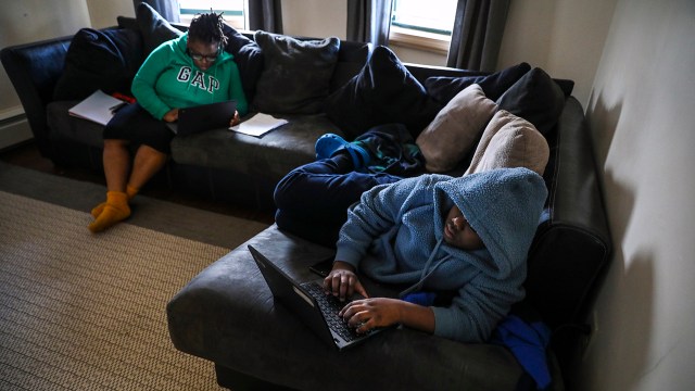 A sixth grader completes his homework online in his family's living room in Boston on March 31, 2020.