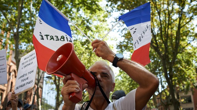 A protester holding French flags shouts into a megaphone at a demonstration against mandatory vaccination in Toulouse, France, on Sept. 4, 2021.