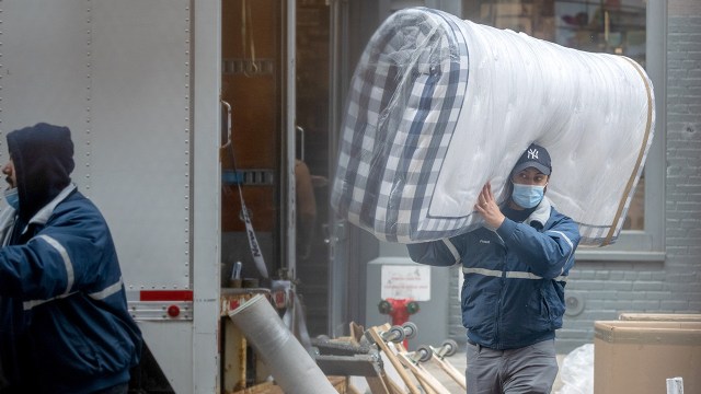 A moving service worker wearing a mask unloads a truck in New York City in March 2021, during the COVID-19 pandemic.