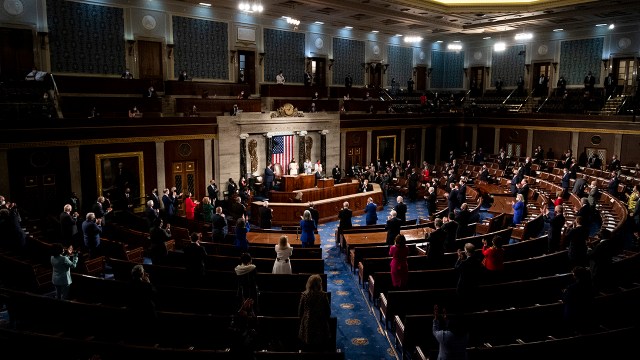 Members of Congress stand as President Joe Biden arrives to deliver his address to a joint session on April 28, 2021.