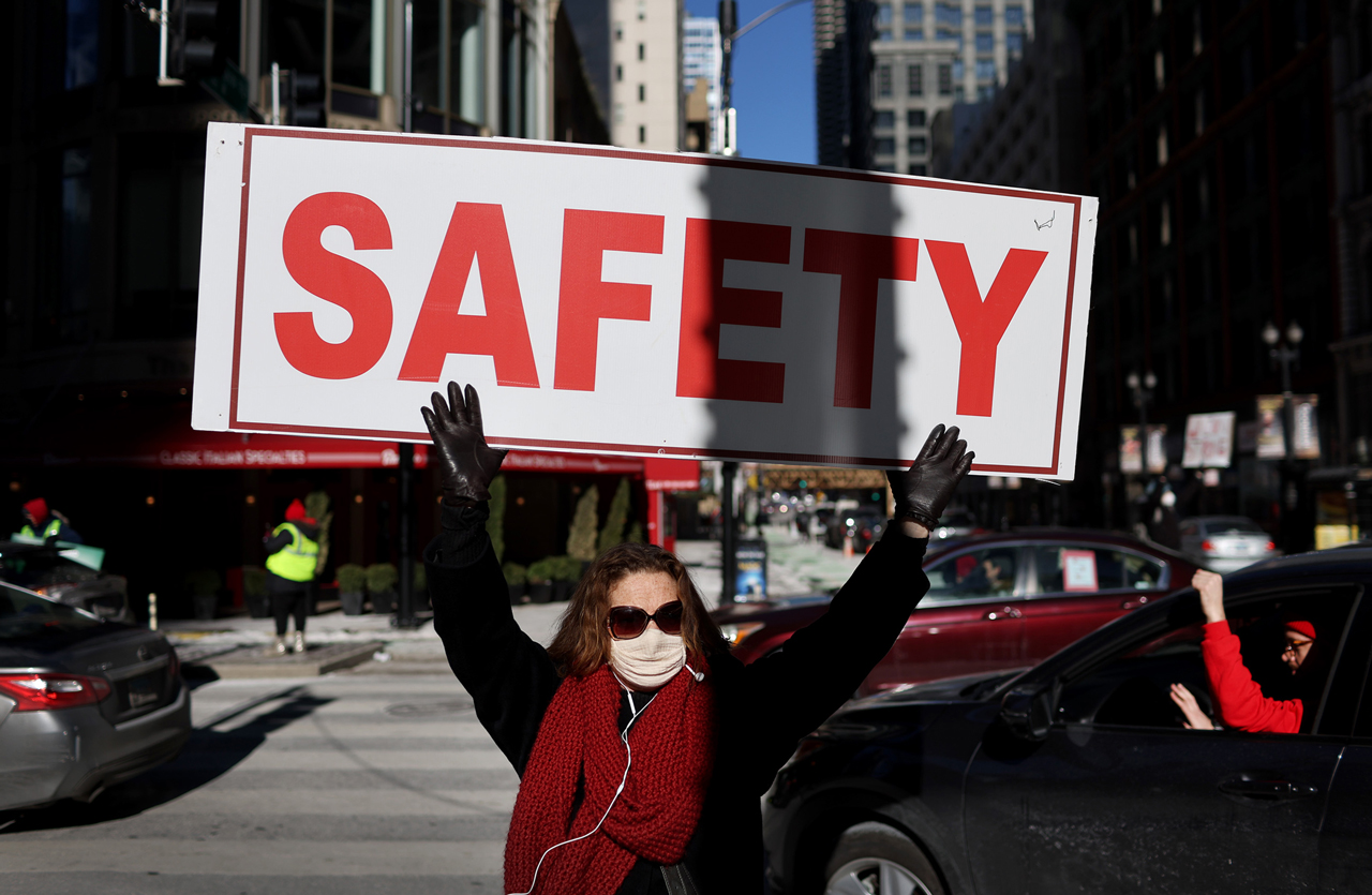 A woman shows her support for a Chicago Teachers Union car caravan around City Hall on Jan. 10, 2022. As COVID-19 cases surged, union members were protesting the continuation of in-person learning in city schools without more safeguards in place.