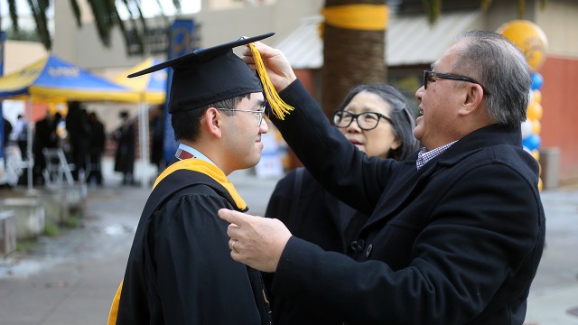 A San Jose State University graduate prepares for commencement ceremonies with his family in December 2021.