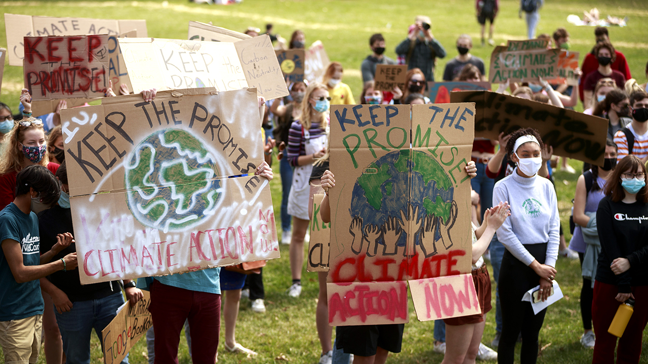Протестующие держат плакаты в поддержку углеродной нейтральности во время митинга «Выполни обещание» в Блумингтоне, штат Индиана, в марте 2021 года.