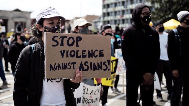 A person holding a sign that says "Stop violence against Asians!" marches at a Stop Asian Hate rally in Oakland, California, on April 3, 2021.