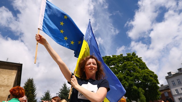 A woman holds Ukrainian and EU flags during the opening ceremony of Free Ukraine Square, next to the Russian embassy in Krakow, Poland, on July 12, 2022.