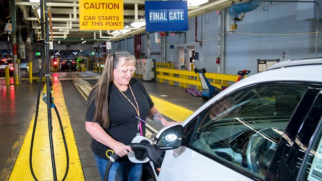 A General Motors employee charges a Chevrolet Bolt EUV on a factory production line in Lake Orion, Michigan, in July 2021.
