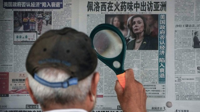 A man reads a newspaper headline reporting on U.S. House Speaker Nancy Pelosi's visit to Asia at a stand in Beijing on July 31.