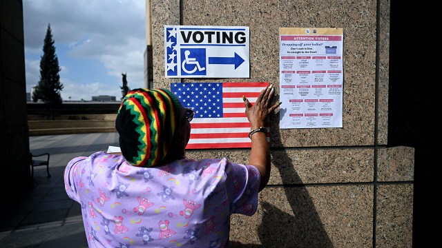 A poll worker hangs signs outside a polling station ahead of the U.S. midterm elections in Los Angeles on Nov. 1, 2022.