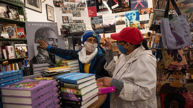 The owner of Marcus Book Store, the oldest Black-owned bookstore in the U.S., talks with her employee about a shop display in Oakland, California, in December 2021. (Amy Osborne/The Washington Post via Getty Images)