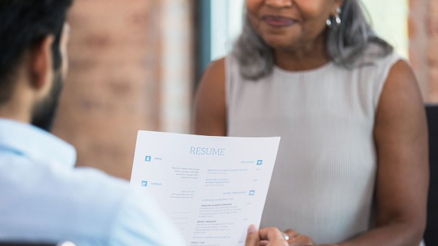 A businessman reads a resume during a job interview with a potential employee.