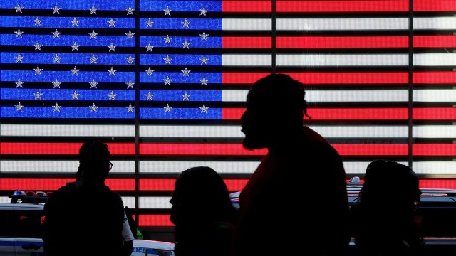 People walk by an American flag in Times Square, New York City. (Leonardo Munoz/AFP via Getty Images)