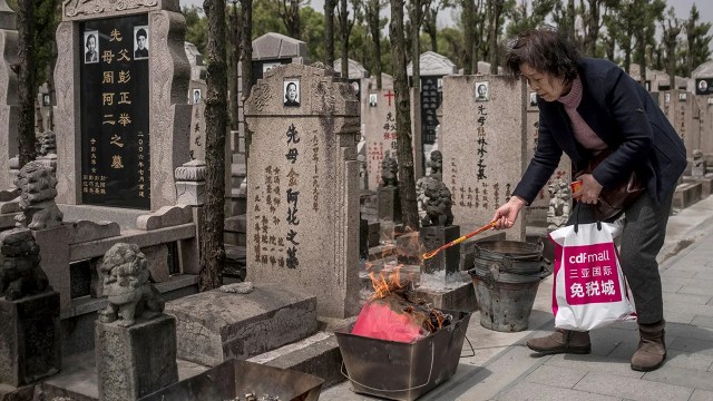 A woman burns an offering of "spirit money" at a gravesite in Shanghai during the Qingming Festival, also known as Tomb Sweeping Day. The ritual is said to benefit dead loved ones in another spiritual realm. This broadly religious custom is common in China, although formal religious affiliation is rare. (Johannes Eisele/AFP via Getty Images)