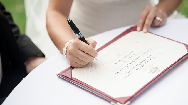 A picture of a bride signing a wedding certificate.