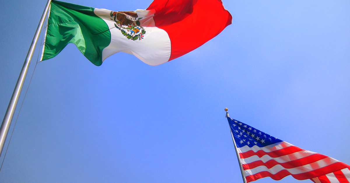 A Mexican and American flag on flagpoles.