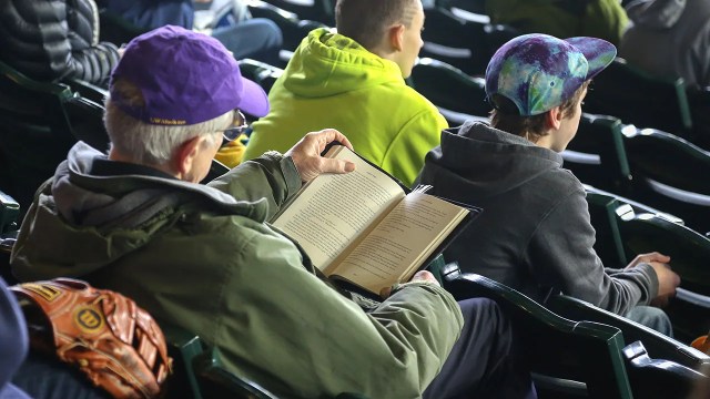 A man reads a book during batting practice before a baseball game. (Otto Greule Jr/Getty Images)