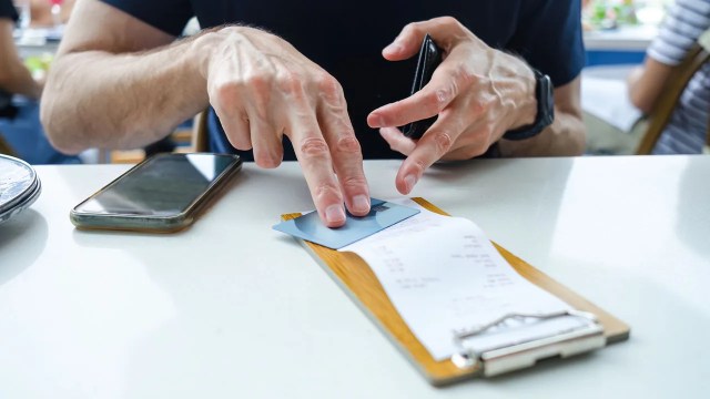 Close-up of unrecognizable white man placing his credit card on top of bill at restaurant.