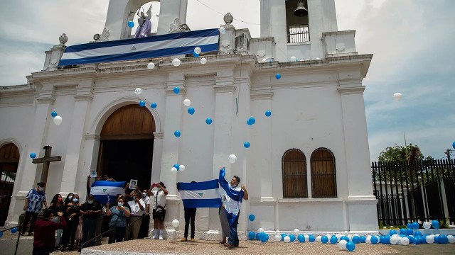 People display national flags outside the Church of San Miguel in Masaya, Nicaragua, on April 18, 2021, to commemorate the third anniversary of the deadly protests against President Daniel Ortega's government. (Maynor Valenzuela/AFP via Getty Images)
