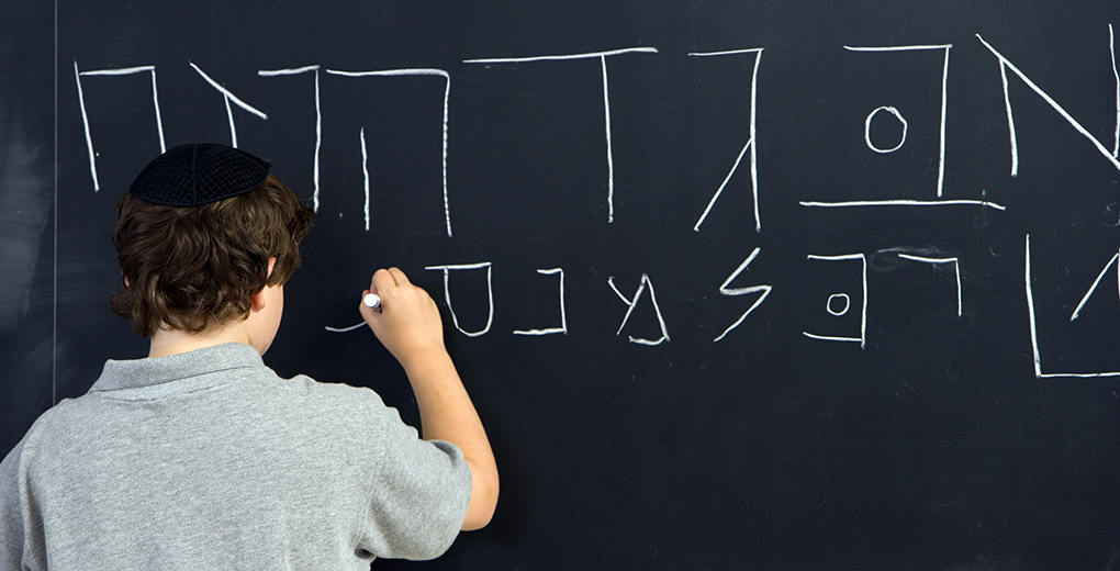 Boy (10-11 years) writing Hebrew on blackboard, rear view