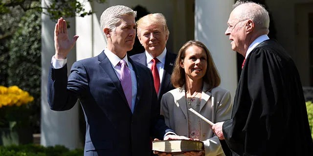 Neil Gorsuch is sworn in as the newest member of the U.S. Supreme Court by Justice Anthony Kennedy in a White House Rose Garden ceremony on April 10, 2017. President Donald Trump, who appointed him, looks on as Gorsuch’s wife, Louise, holds the Bible. (Xinhua/Yin Bogu via Getty Images)