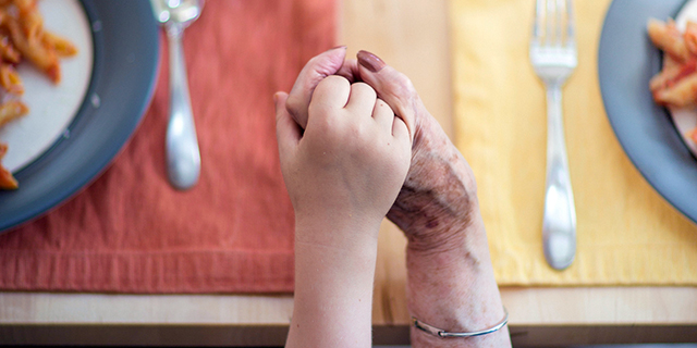 Grandmother and grandson holding hands at dinner table