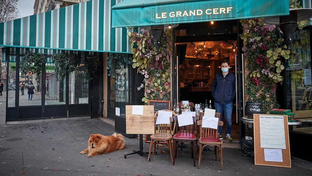 Owner Alexi Monen stands in the doorway of his Paris cafe selling a table and some chairs on Feb. 1, 2021. Restaurants in France have been closed to indoor dining since October. (Kiran Ridley/Getty Images)