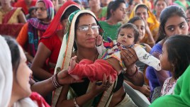 Woman holds a baby at rally on International Women's Day in 2018 in Jhunjhunu, India.