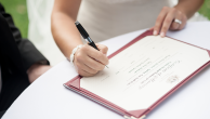 A picture of a bride signing a wedding certificate.