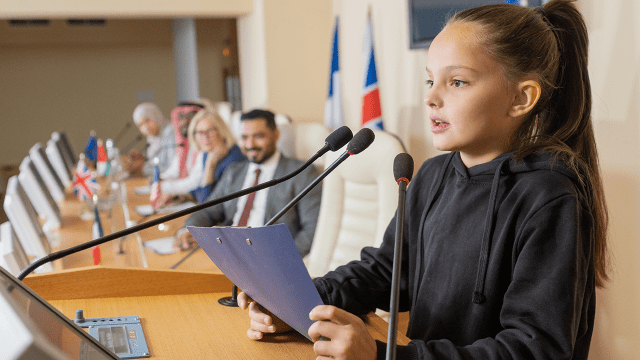 Schoolgirl with clipboard speaking in microphone (Shironosov)