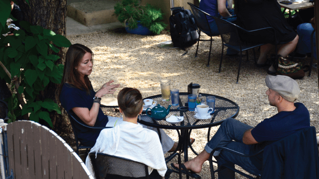 Three people talk over tea and coffee outside a restaurant in Santa Fe, New Mexico.