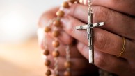 Woman praying with rosary beads in hands