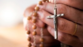 Woman praying with rosary beads in hands